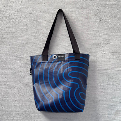 Tote bag with blue wave pattern on a gray textured background