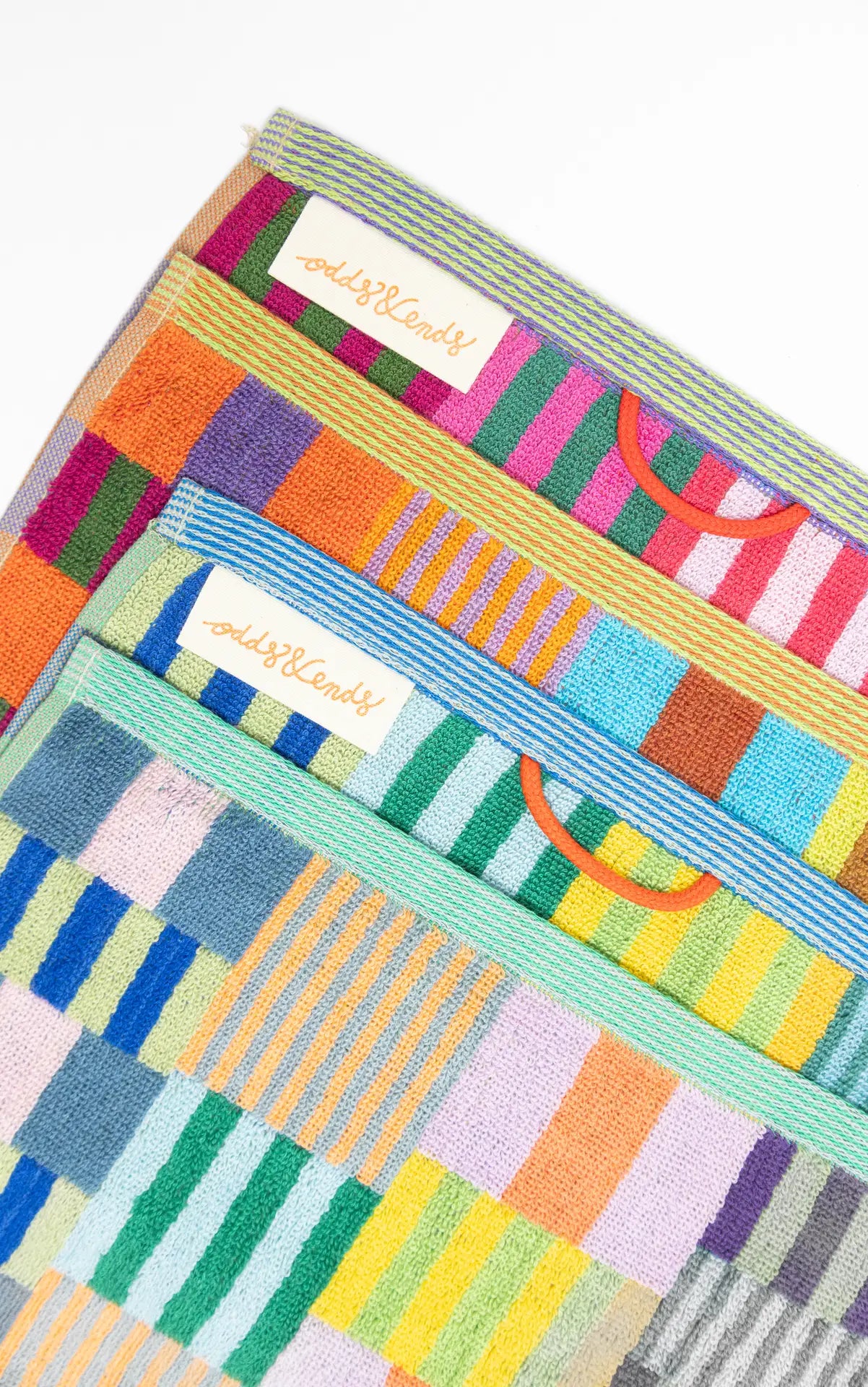 Colorful patterned towels with branding on a white background