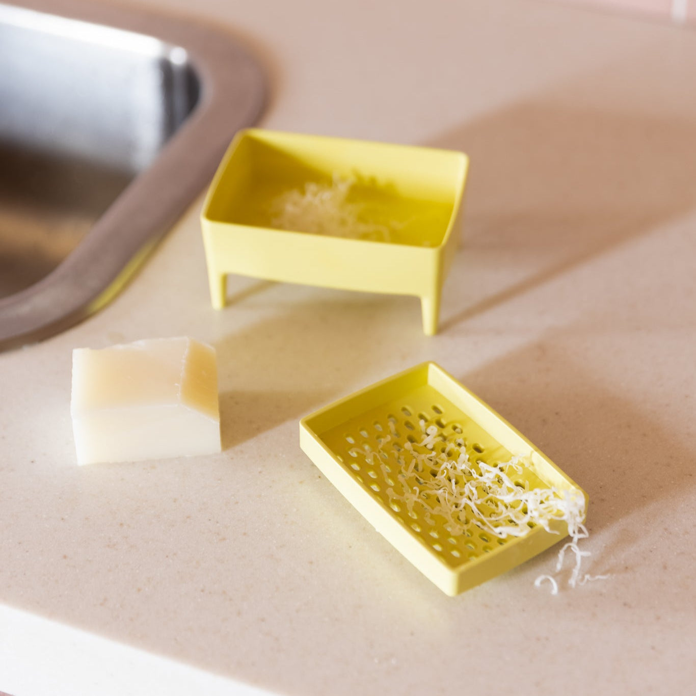 Yellow soap dishes with soap shavings on a kitchen counter.
